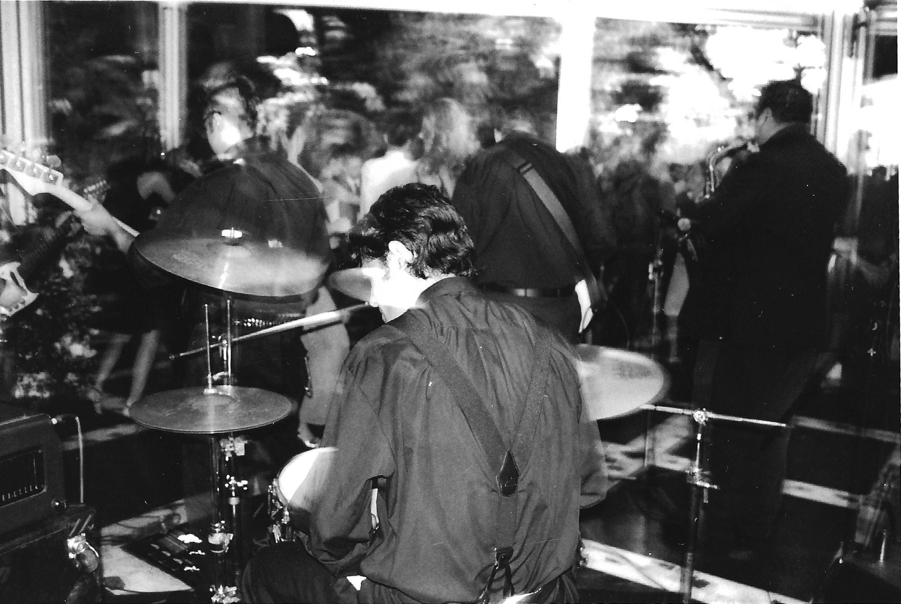 Eduardo Guerrero playing live, seen from behind his drum kit, with the band and the crowd in front of him