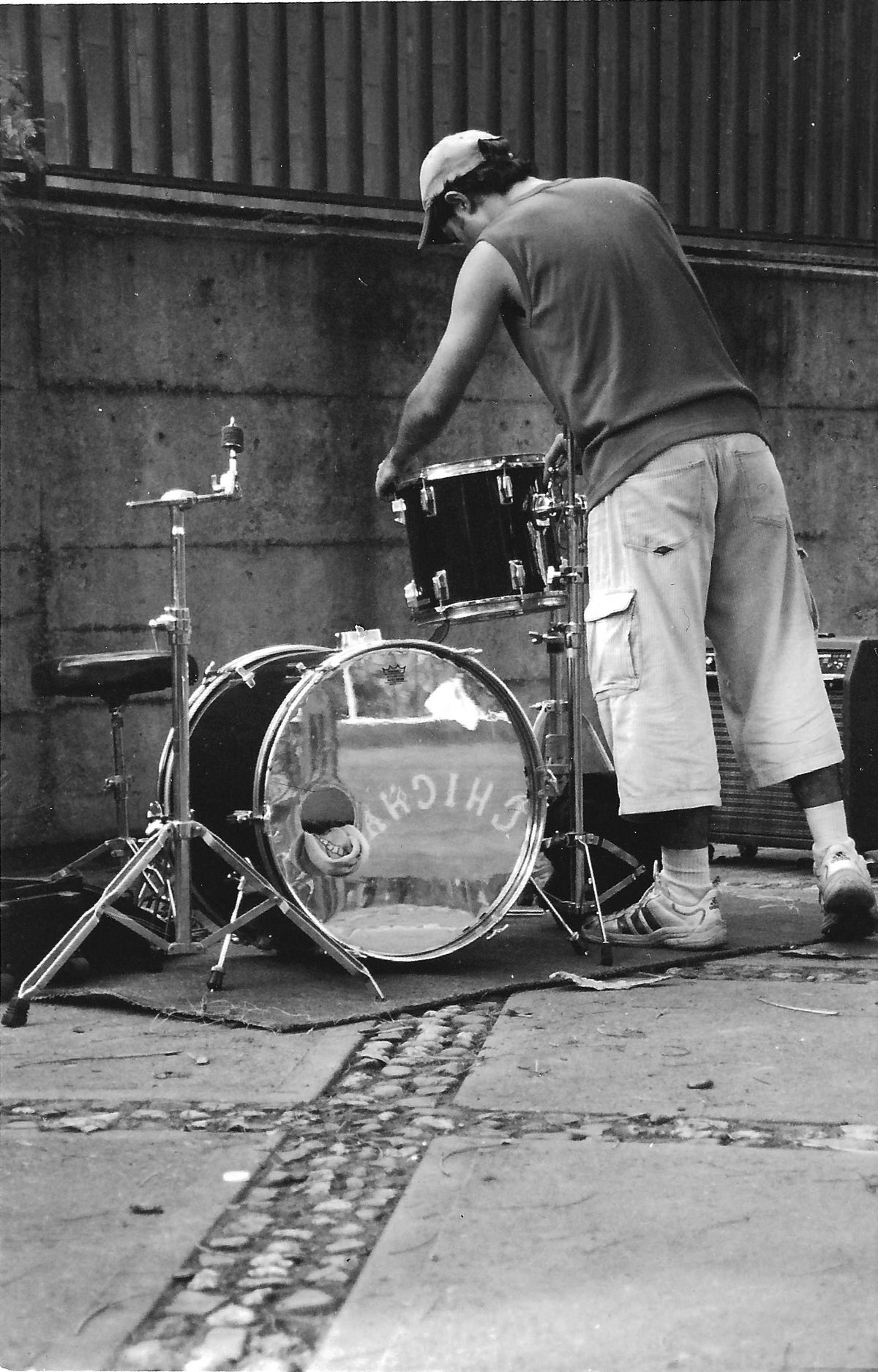 Eduardo setting up his drum kit outdoors before a show; the mirror bass drum head reflects the street